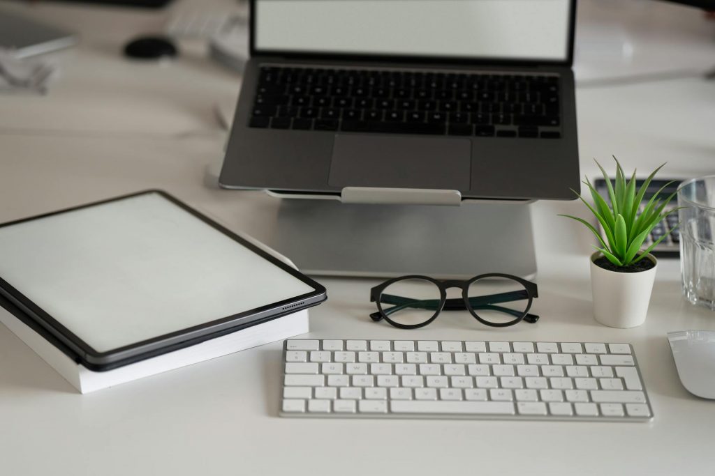 Photo from some glasses, keyboard, laptop and other working tools.
